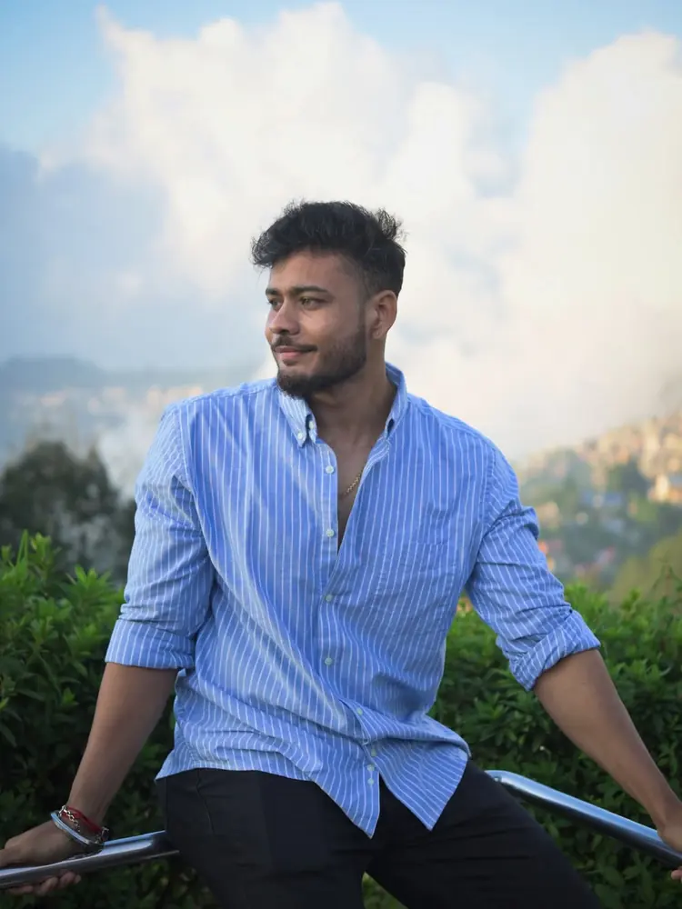 Mayukh looking to the side with hills and clouds behind him